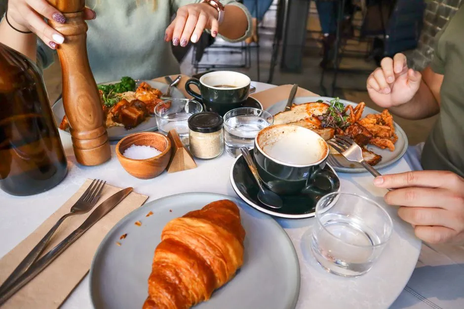Friends sharing a casual brunch spread of croissants and coffee at an outdoor table